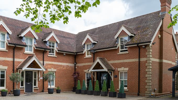 Red-brick Levitas Clinic building in Guildford with gabled entrance porches and clipped topiary in planters