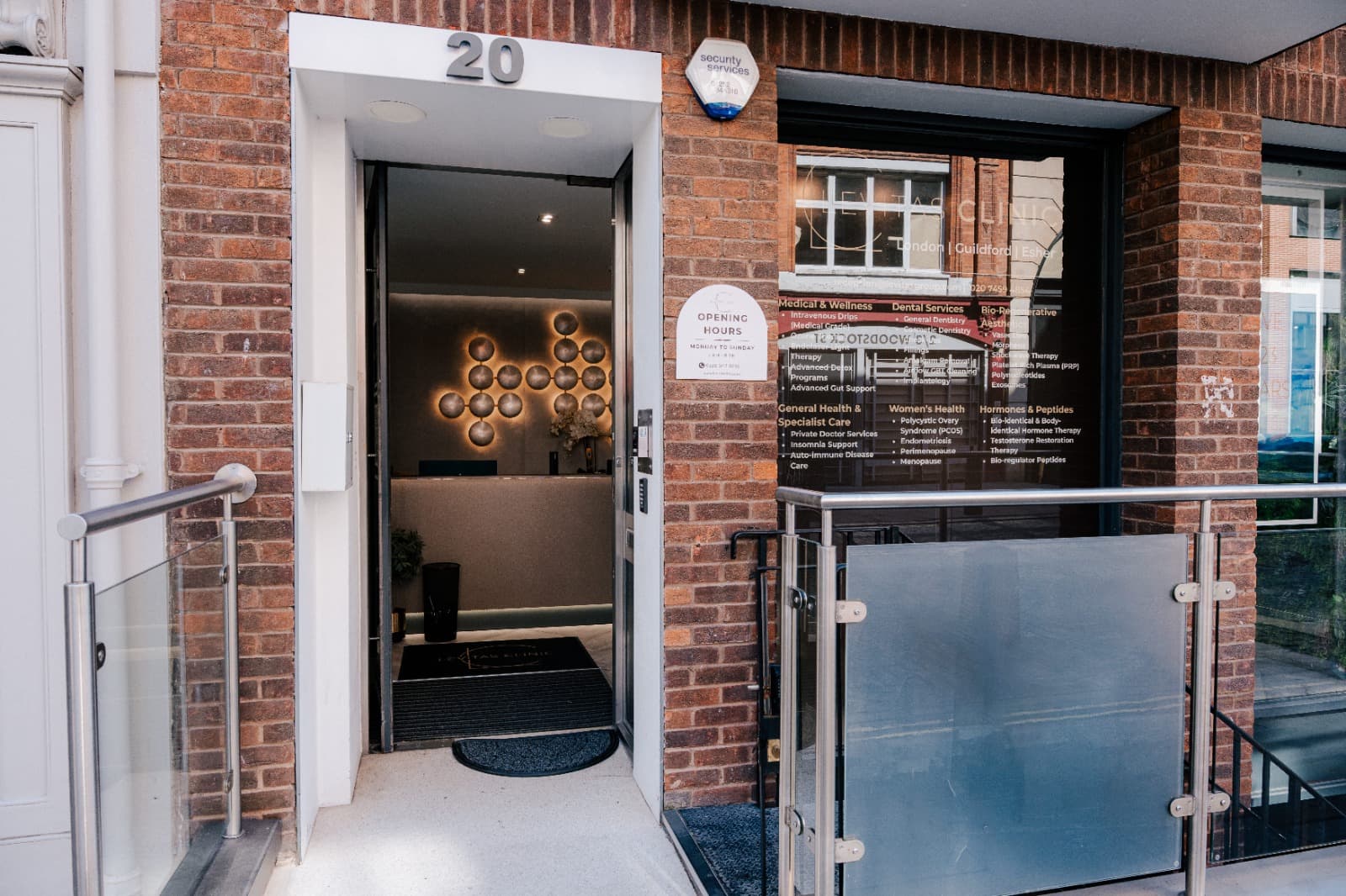 Entrance to Levitas Clinic London on Woodstock Street: an open door at number 20 leading to a softly lit reception with gold discs on the wall, beside a window listing services