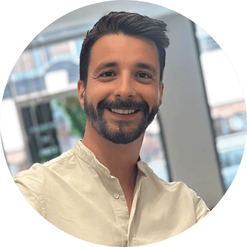 Dr Federico Fedel smiling, with dark hair and a beard, wearing a cream collarless shirt