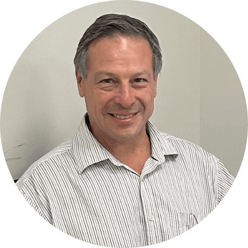 Dr Jonathan Miller smiling, with short greying hair, wearing a striped shirt