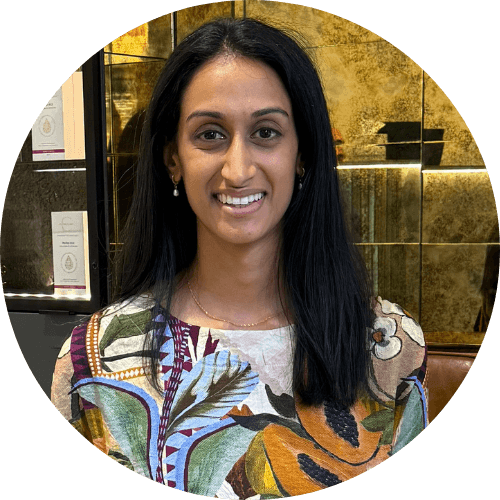 Dr Madhvi Patel smiling, with long dark hair, wearing a colourful patterned blouse