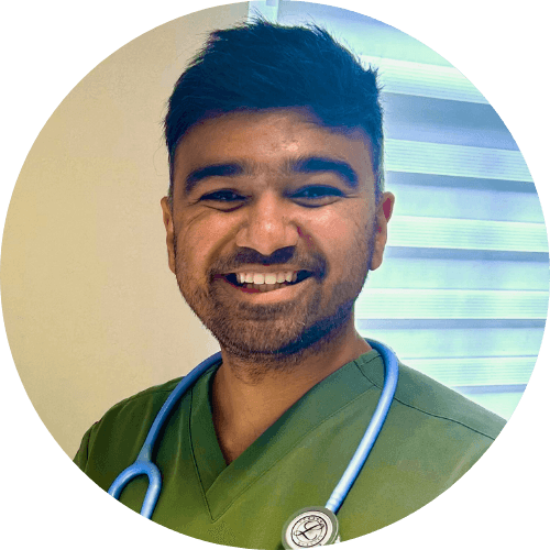 Dr Vijay Prakash smiling, in green scrubs with a stethoscope around his neck
