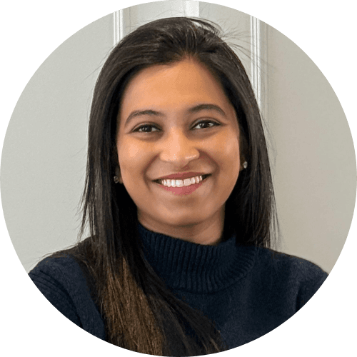 Dr Gunjan Modi smiling, with long dark hair, wearing a navy roll-neck jumper