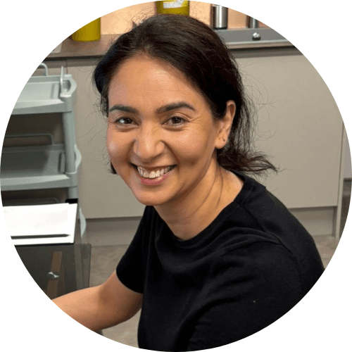 Dr Kiran Dhillon smiling, with dark hair tied back, wearing a black top