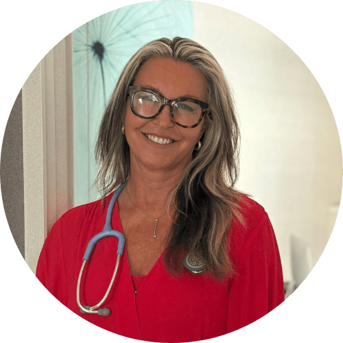Dr Simone Kuter smiling, with long fair hair and tortoiseshell glasses, wearing a red top and a stethoscope