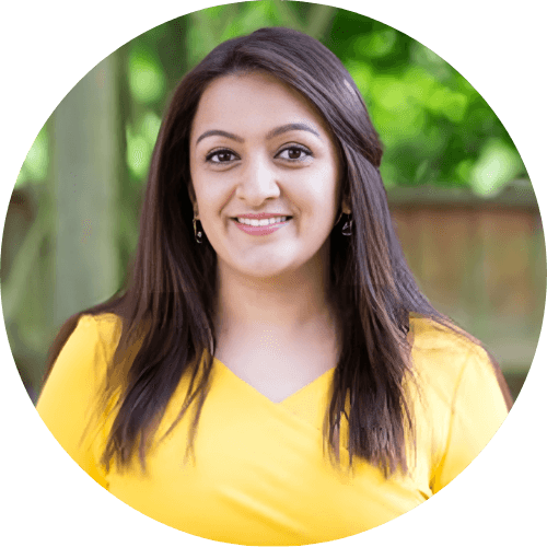 Dr Sonia Panchal smiling, with long dark hair, wearing a yellow top in a garden